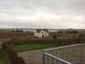 a white house in a field with a fence at 16 East Street Sandwick Stornoway in Sandwick