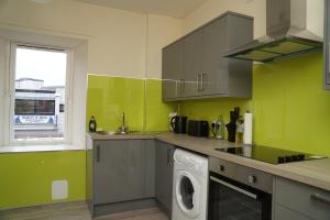 a green kitchen with a washing machine in it at Spacious Home Dundee in Dundee