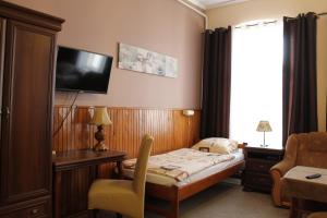 um quarto de hotel com uma cama e uma televisão na parede em Hotel Polonia em Namyslów