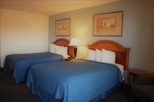 ein Hotelzimmer mit 2 Betten und einem Stuhl in der Unterkunft Texas Inn & Suites in Denton
