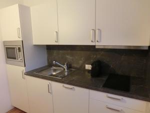 uma cozinha com armários brancos e um lavatório em Ausblick em Längenfeld
