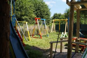 a playground with colorful swings in the grass at Domki " ELRINO " in Jastarnia