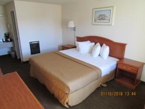 a hotel room with a bed with white sheets and pillows at Western Inn - Green River in Green River