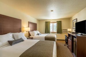 um quarto de hotel com duas camas e uma televisão de ecrã plano em Cobblestone Inn & Suites - Merrill em Merrill
