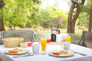 una mesa con platos de comida y vasos de zumo de naranja en Southern Sands Eco Lodge, en Hoedspruit