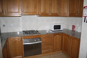 a kitchen with wooden cabinets and a stove and a microwave at Arquinha Apartment in Ponta Delgada +42 photos