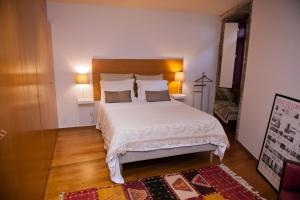 1 dormitorio con 1 cama grande con sábanas y almohadas blancas en Civitá Design & Accommodation en Braga
