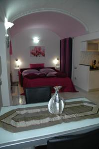 アマルフィにあるCasa Duomoのベッドルーム1室(赤いベッド1台、テーブルの上に花瓶1枚付)
