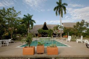 a swimming pool with chairs and trees and a house at Casa los Almendros in Guamo