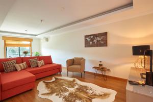 a living room with a red couch and a chair at BeGuest Arribamar Apartment in Cascais