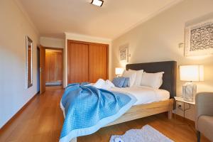 a bedroom with a bed with a blue blanket on it at BeGuest Arribamar Apartment in Cascais