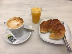 a plate with a cup of coffee and a croissant at Pensión Régil in San Sebastián