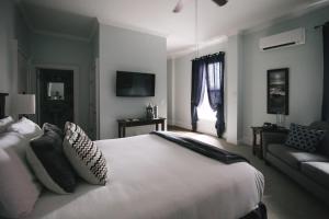Un dormitorio con una gran cama blanca y un sofá. en The Continental Hotel, en Centerville