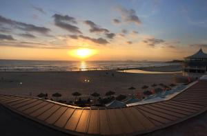 a sunset on a beach with umbrellas and the ocean at Entre o Mar e Lisboa in Oeiras