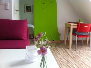 a living room with a couch and a table with flowers at Ferienwohnung Schau ins Dorf in Ostercappeln +11 photos