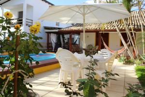 - une terrasse avec des chaises blanches et un parasol à côté de la piscine dans l'établissement Casa Pousada Rosa dos Ventos, à Florianópolis