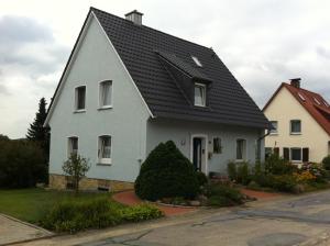 a white house with a black roof at Ferienwohnung Schau ins Dorf in Ostercappeln