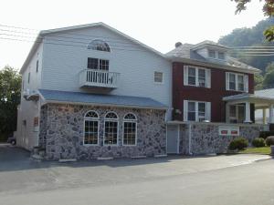 a large white house with a stone wall at Maria's Garden & Inn in Berkeley Springs