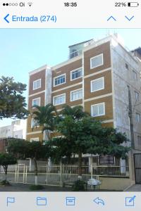 a large brick building with trees in front of it at Apartamento Temporada Enseada in Guarujá