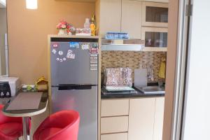 eine Küche mit einem Kühlschrank und einem Tisch mit roten Stühlen in der Unterkunft Green Bay Pluit Apartment - Indra in Jakarta