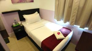 Un pequeño dormitorio con una cama con una toalla. en Apple 1 Hotel Queensbay, en Bayan Lepas