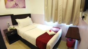 a hotel room with a bed with a towel on it at Apple 1 Hotel Queensbay in Bayan Lepas