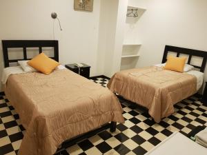 two beds in a room with a checkered floor at Hostal Le Prince in Tacna