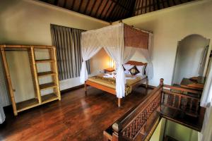 a bedroom with a canopy bed and a wooden floor at Ben's Homestay in Ubud