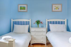 two beds in a room with blue walls at Tolly House in Wells next the Sea