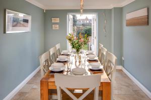 a dining room with a long table with white chairs at Tolly House in Wells next the Sea
