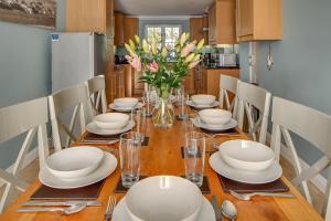 a dining room table with white dishes and a vase of flowers at Tolly House in Wells next the Sea