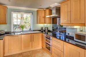 a kitchen with wooden cabinets and black counter tops at Tolly House in Wells next the Sea