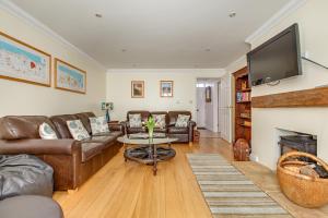 a living room with leather furniture and a flat screen tv at Tolly House in Wells next the Sea