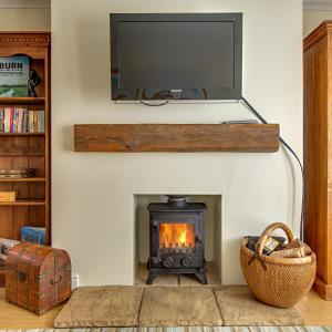 a living room with a fireplace with a television above it at Tolly House in Wells next the Sea