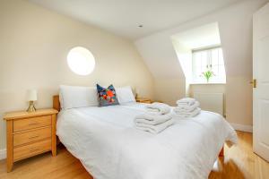 a bedroom with a white bed with towels on it at Tolly House in Wells next the Sea