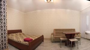 a bedroom with a bed and a table and a chair at Baikal Apartments Central in Krasnoyarsk