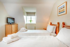 a bedroom with two beds and a tv on a dresser at Tolly House in Wells next the Sea