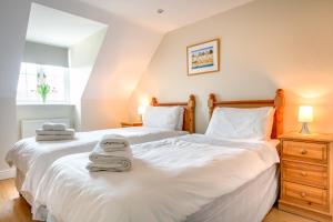 two beds in a bedroom with towels on them at Tolly House in Wells next the Sea