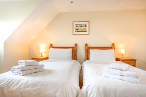 two beds in a room with white towels on them at Tolly House in Wells next the Sea