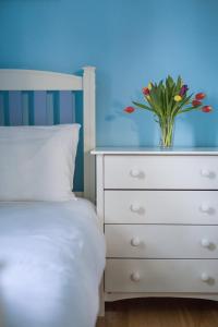 a bedroom with a white dresser with a vase of flowers on it at Tolly House in Wells next the Sea