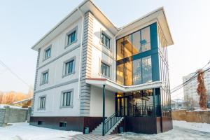 a large white building with glass windows at Keremet Hotel in Almaty