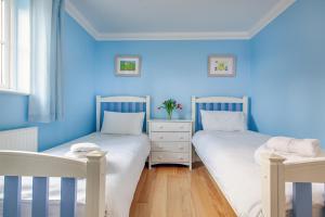 two beds in a room with blue walls at Tolly House in Wells next the Sea