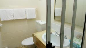 y baño con aseo, lavabo y ducha. en The Islands Inn Motel, en Airlie Beach