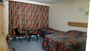 um quarto com uma cama, uma mesa e cadeiras em The Islands Inn Motel em Airlie Beach