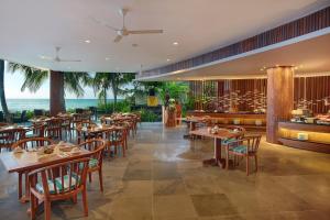 Un restaurante con mesas y sillas y el océano. en Candi Beach Resort & Spa, en Candidasa
