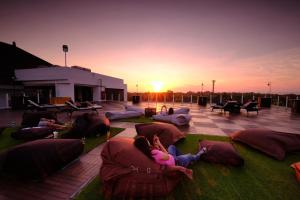 a group of people laying on pillows on a patio with the sunset at The Sintesa Residence Jimbaran in Jimbaran