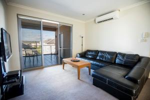 a living room with a black leather couch and a table at Zappeion Apartments in Perth