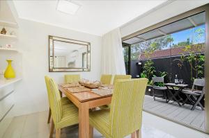 a dining room with a wooden table and chairs at Kananda in Noosa Heads