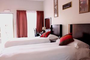 a hotel room with two beds with red pillows at The Lazy Grape Guest Lodge & Spa in Benoni