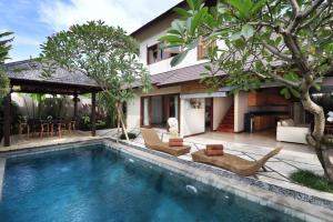 a villa with a swimming pool and a house at Desa Di Bali Villas in Kerobokan
